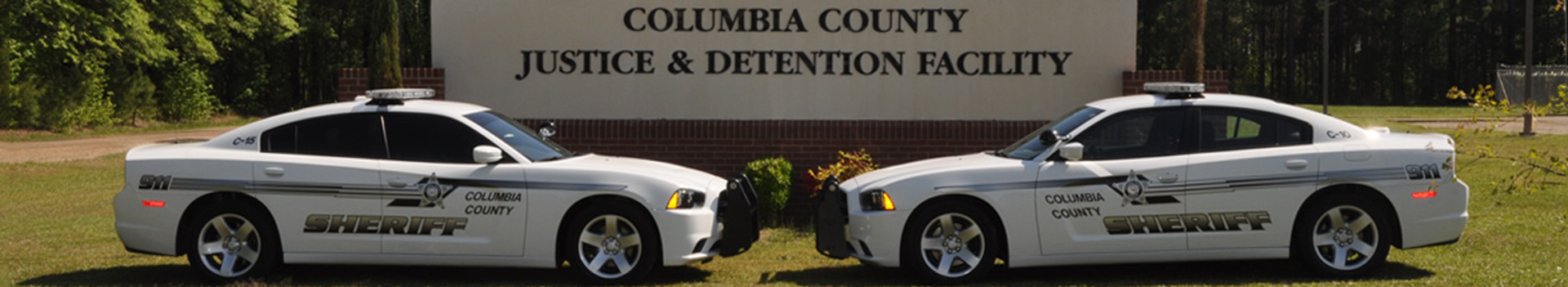 Two squad cars parked in front of the Columbia County Justice and Detention Facility